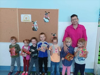 dzieci trzymające kartki stoją z wychowawczynią