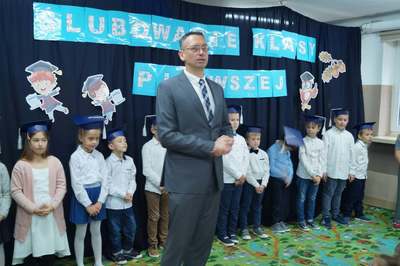 Dyrektor szkoły stoi wśród uczniów klasy pierwszej
