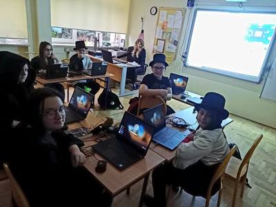 dzieci siedzą w klasie, pracują przy laptopach