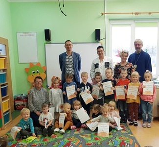 Stoją nauczyciele i uczniowie z dyplomami