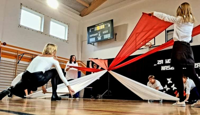nauczyciele i uczniowie trzymają flagę Polski