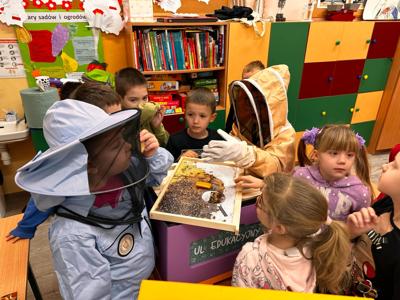 Grupa dzieci podczas zajęć edukacyjnych przy ulu. 