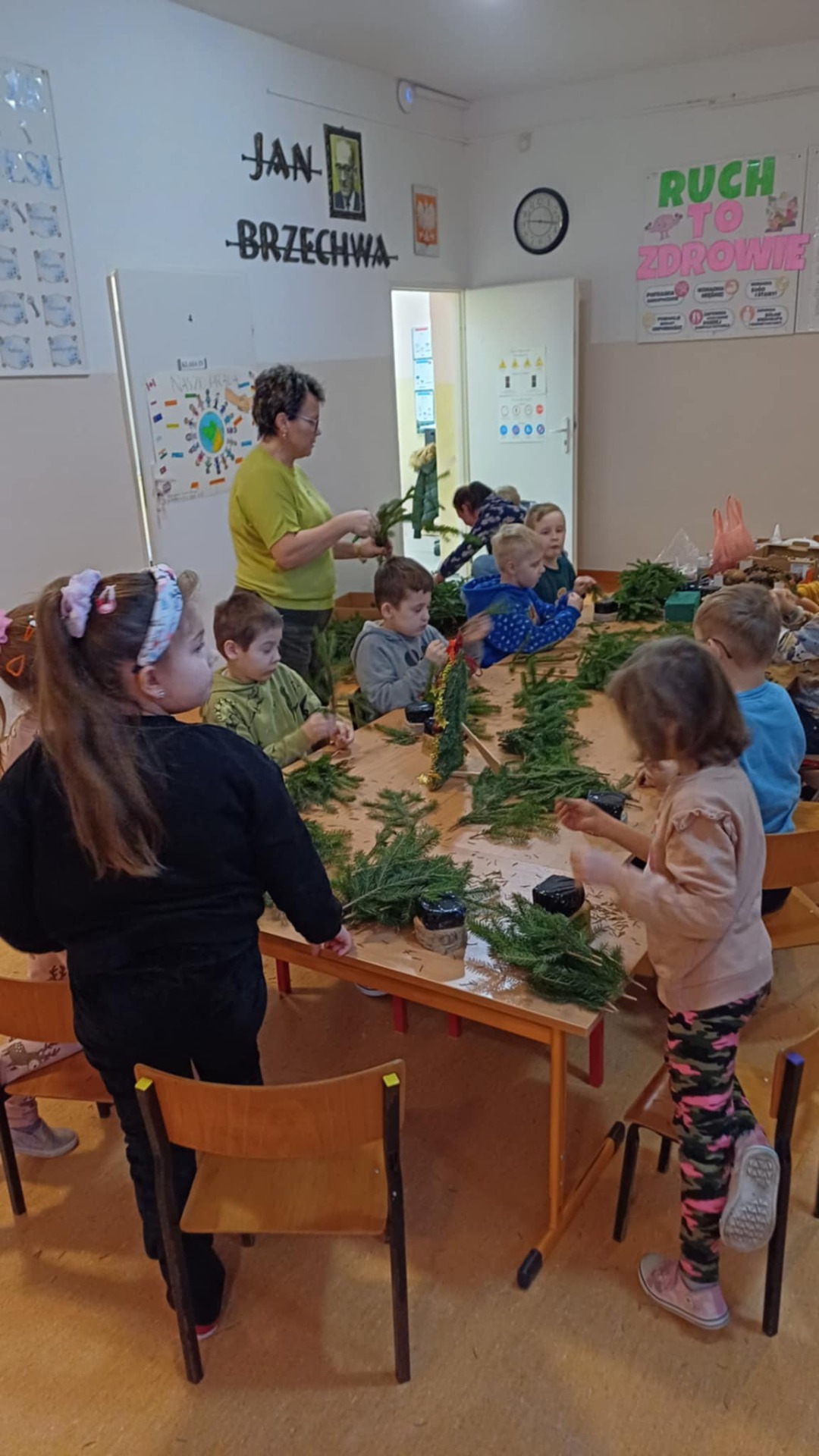 Na zdjęciu uczniowie kl. I wykonujący stroiki świąteczne z wychowawcą klasy i rodzicami.