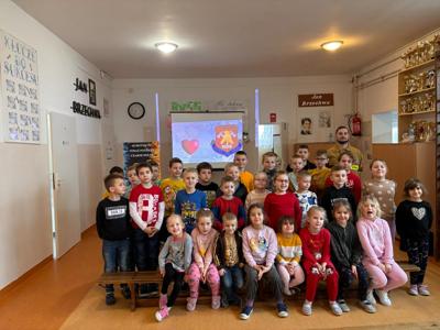 Zdjęcie grupowe. Uczniowie ze strażakiem prowadzącym zajęcia nt. bezpieczeństwa podczas ferii zimowych. 