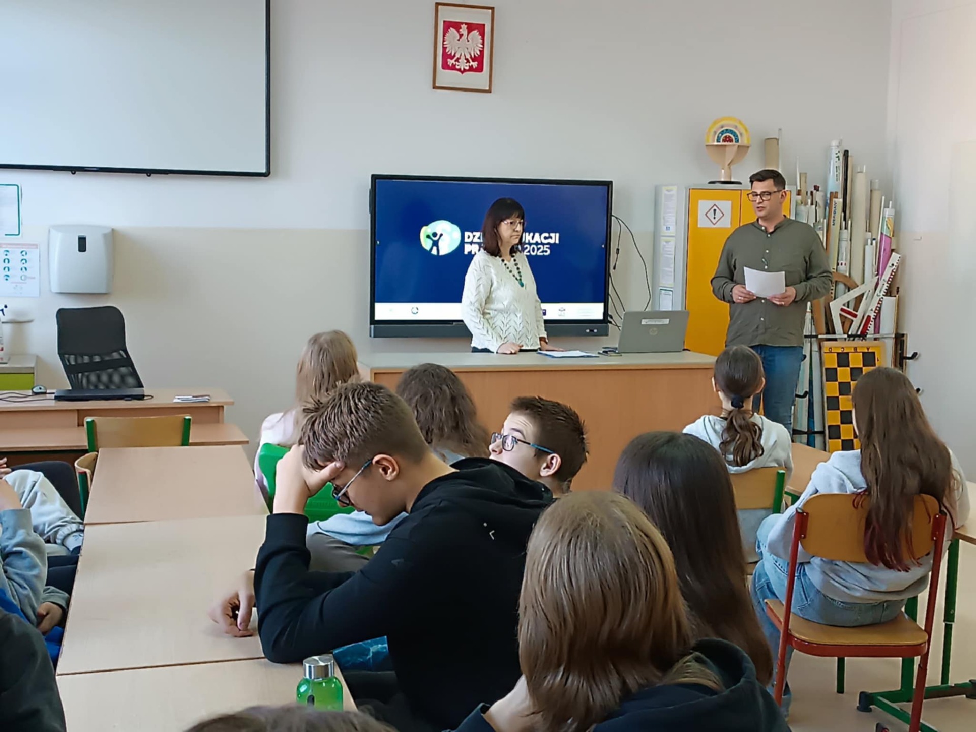 Na zdjęciu notariusz prowadzący zajęcia, nauczyciel szkoły i uczniowie biorący udział w lekcji.