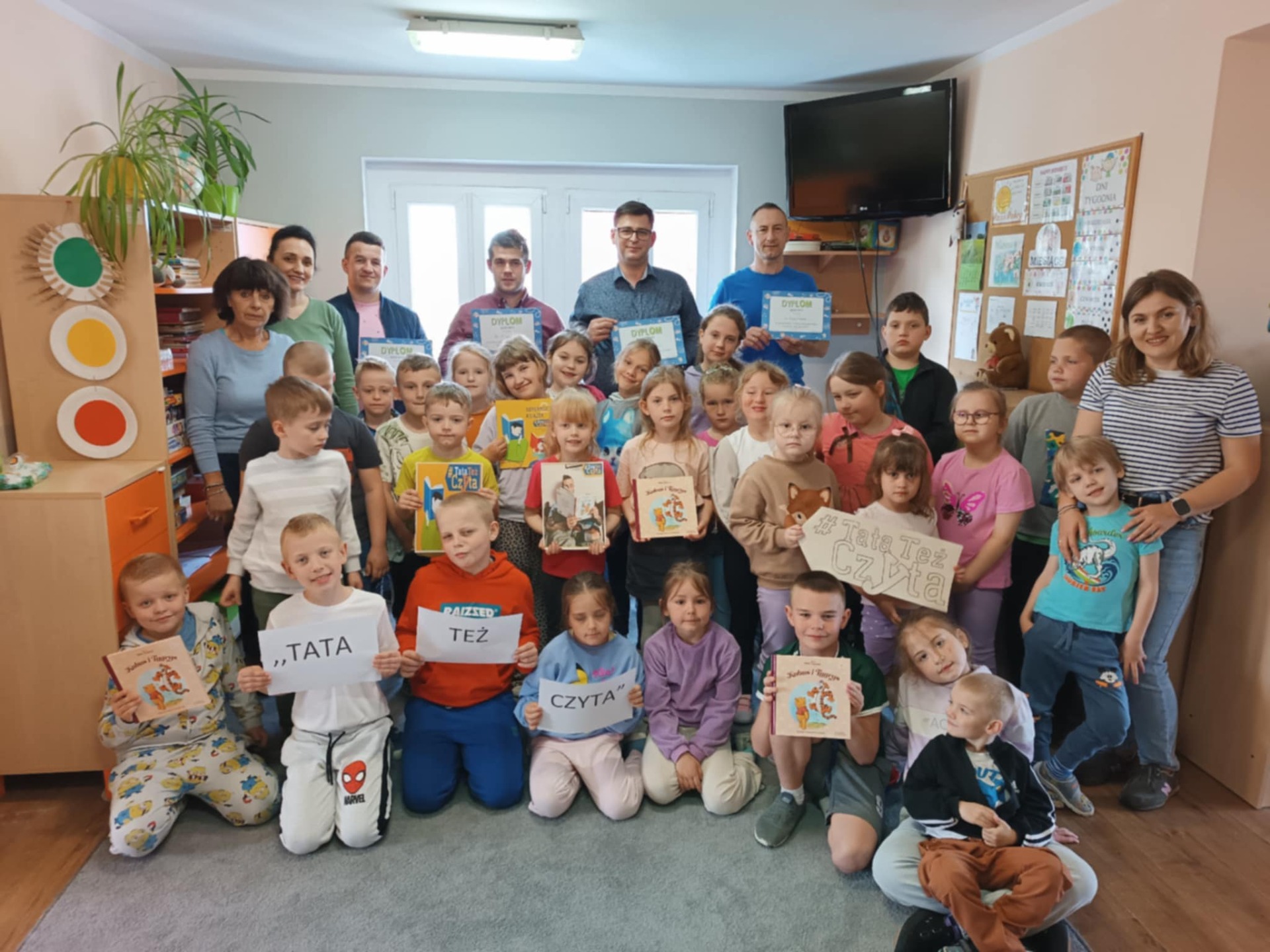 Grupowe zdjęcie przedstawiające Dzieci, rodziców i nauczycieli biorących udział w ogólnopolskiej akcji czytelnictwa.