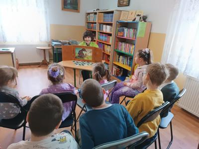 Zajęcia uczniów kl. I w bibliotece. Na zdjęciu nauczyciel prowadzący zajęcia i uczestniczące w nich dzieci. 