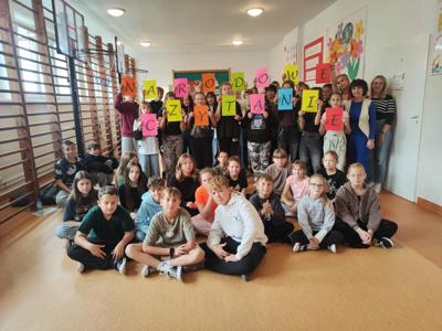 Na zdjęciu uczniowie klas IV - VIII wraz z nauczycielkami języka polskiego na tle gazetki czytelniczej.