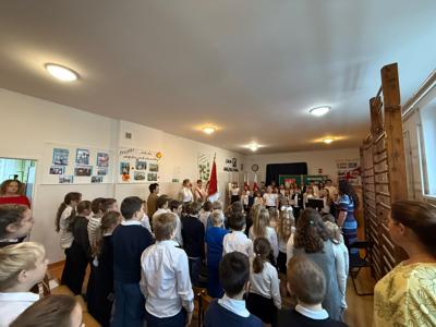 Uczniowie, nauczyciele i pracownicy szkoły podczas śpiewania hymnu państwowego