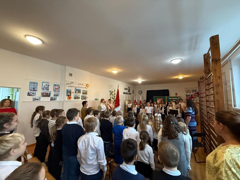 Uczniowie, nauczyciele i pracownicy szkoły podczas śpiewania hymnu państwowego