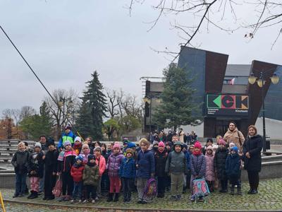 Uczniowie klas 0-3 ustawieni na tle budynku Kwidzyńskiego Kino -  Teatru wraz z opiekunami wyjazdu.